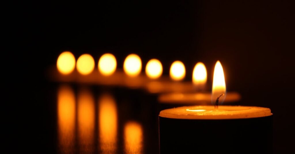 A close-up view of tealight candles reflecting a warm glow in the dark.