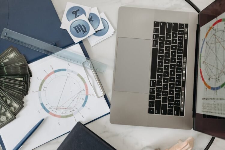 Astrology chart, laptop, and tarot cards on a desk, study of celestial influences.