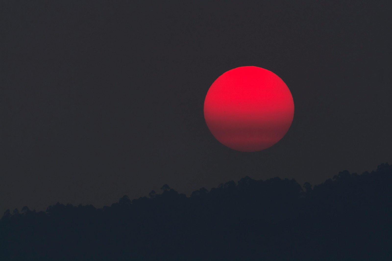 A captivating blood moon rising over a silhouette of hills, capturing the beauty of twilight.